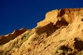 Natural sandstone formations: formed from cemented sand grains, yellow-orange in colour, forming rough cliffs against bright blue Royalty Free Stock Photo